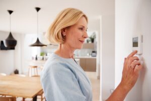 woman-adjust-temperature-on-smart-thermostat